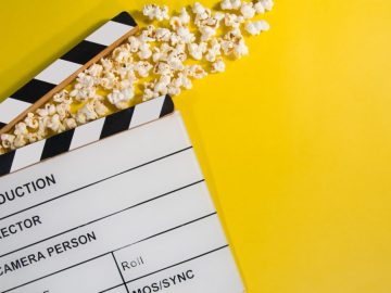 Filmklappe und Popcorn auf gelbem Grund