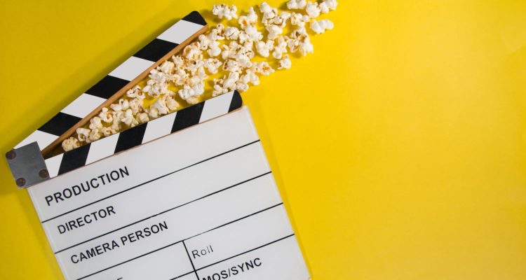 Filmklappe und Popcorn auf gelbem Grund