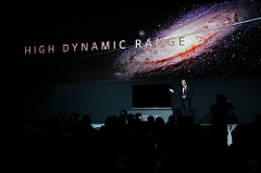 Ein Mann im Anzug zeigt auf einen Dolby Vision HDR-Fernseher