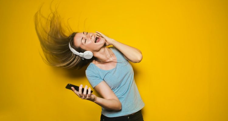 Frau hört begeistert Musik über Bluetooth-Kopfhörer