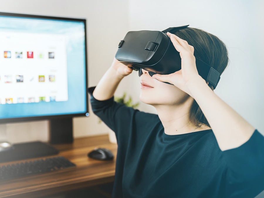 Frau mit VR-Brille vor Computer