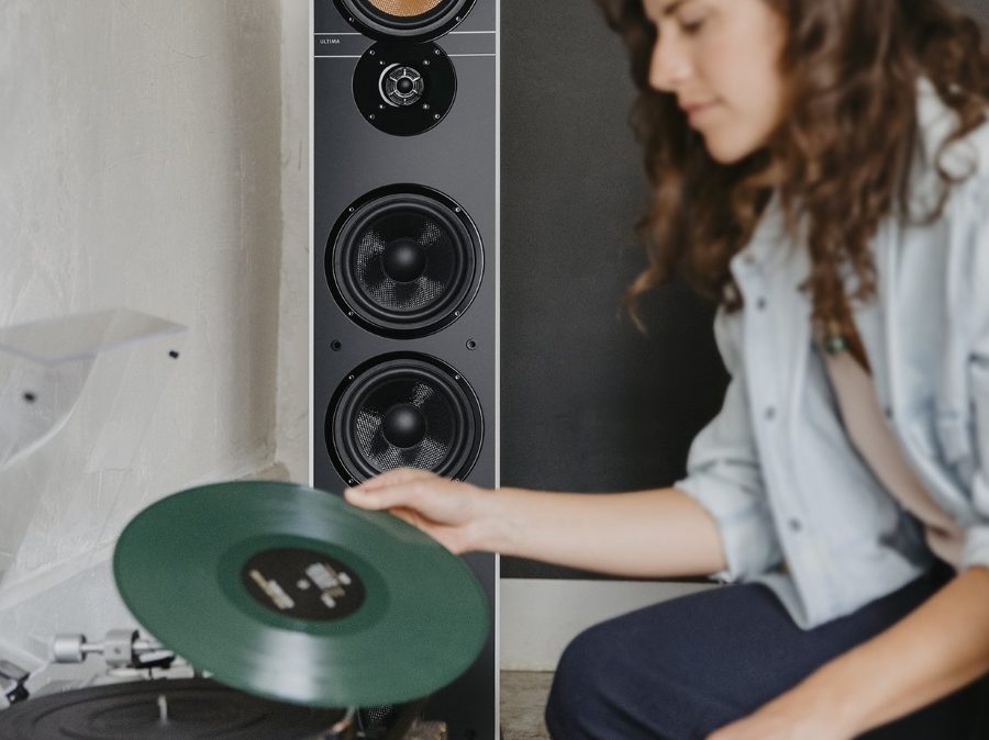 Frau legt Vinyl in Plattenspieler, im Hintergrund Lautsprecher