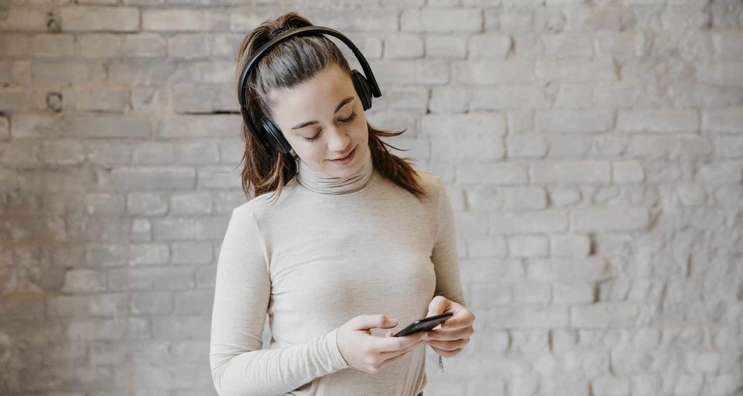 Frau spielt Handygames mit Bluetooth Kopfhörer