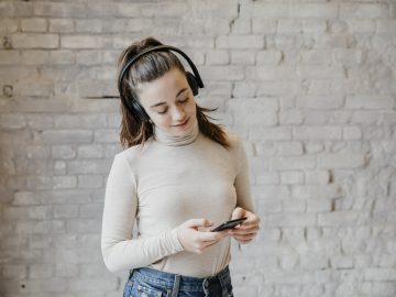 Frau spielt Handygames mit Bluetooth Kopfhörer