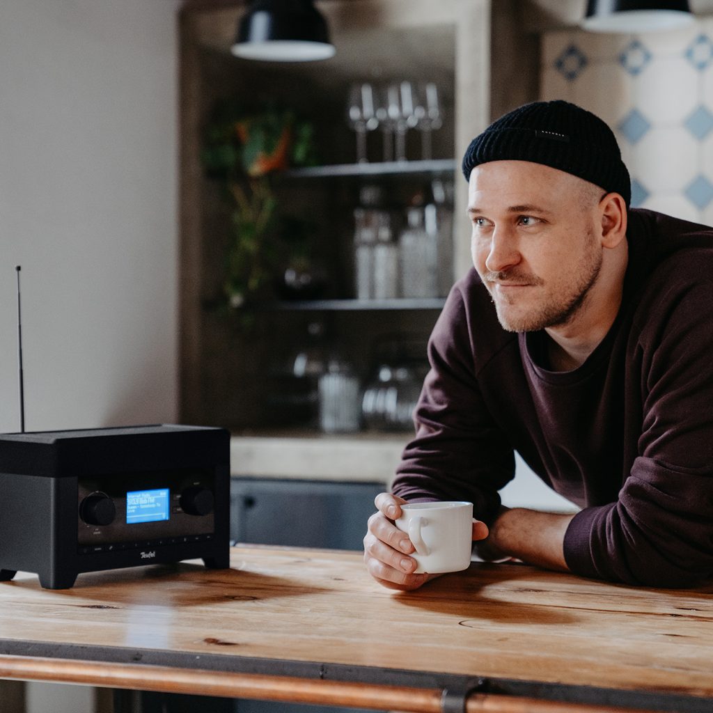 Mann trinkt Kaffee und hört Radio.