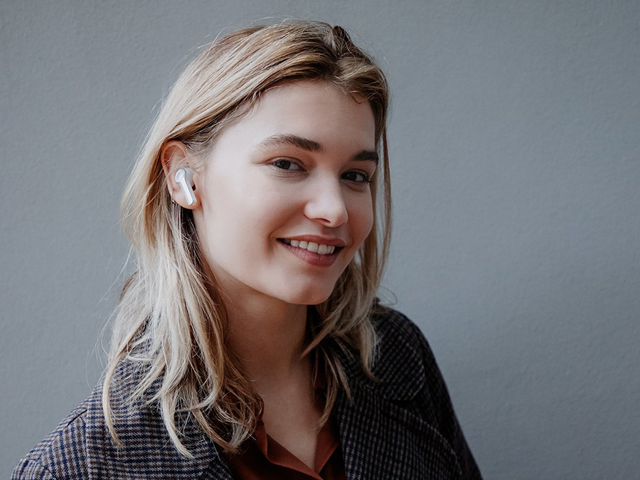 Lächelnde Frau mit True Wireless In-Ear-Kopfhörern AIRY TRUE WIRELESS