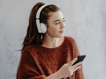 Junge Frau mit Kopfhörer und Smartphone.