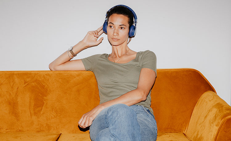 Mujer sentada en el sofá con auriculares Bluetooth SUPREME ON de Teufel