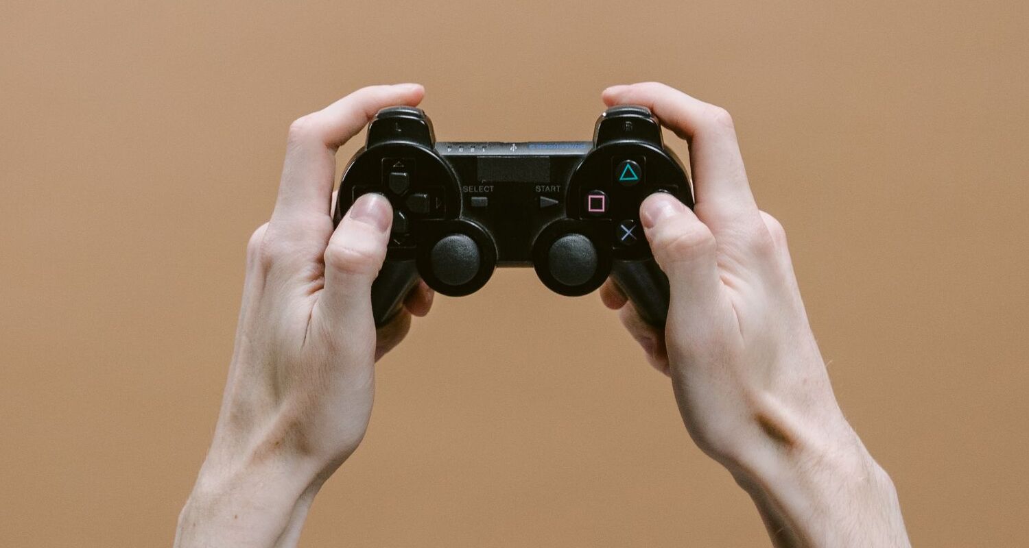 Hände halten einen schwarzen PlayStation-Controller