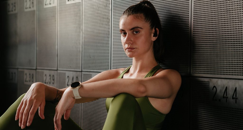 Frau in Sportkleidung trägt Polar Ignite 2 und Teufel Airy Sports TWS