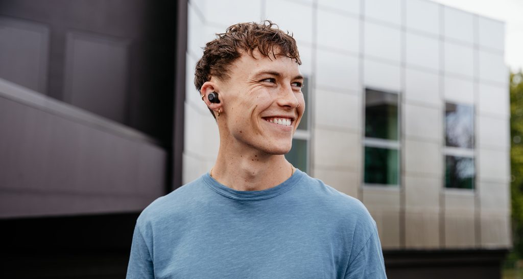 Lachender junger Mann draußen mit True Wireless In-Ears REAL BLUE TWS
