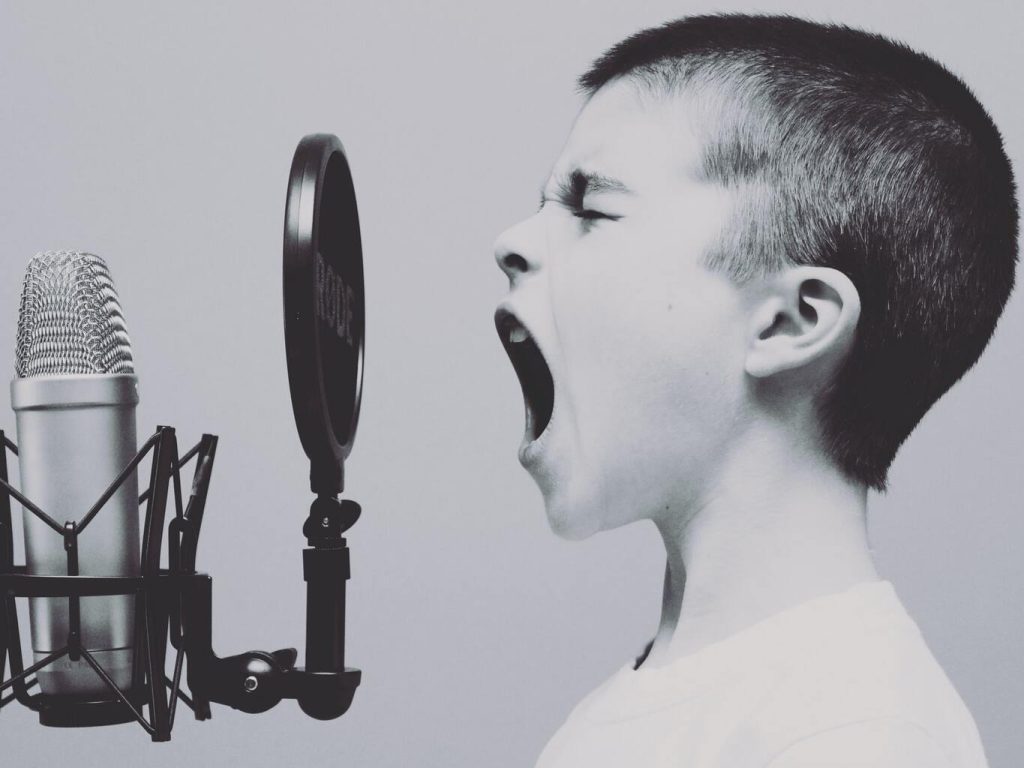 Junge schreit durch ein Popschutz ins Mikrofon