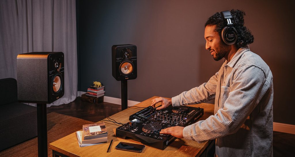 Junger Mann bedient DJ-Controller von Pioneer, trägt dabei DJ-Kopfhörer von Teufel