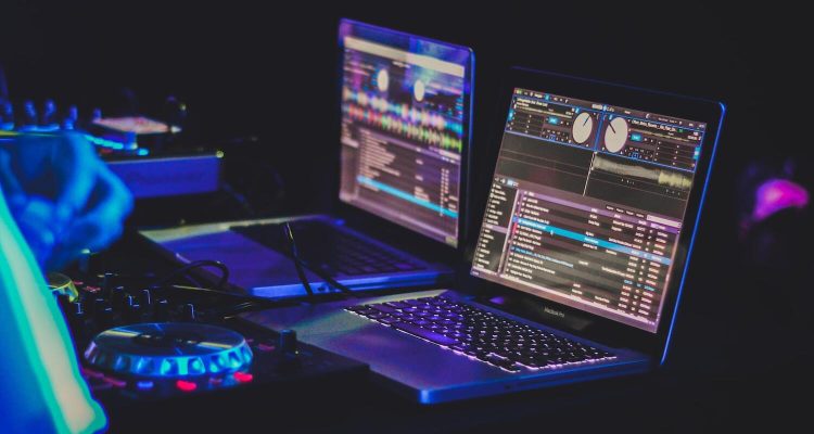 DJ-Set-up mit Controller und 2 Macbooks, auf denen eine DJ-Software läuft.