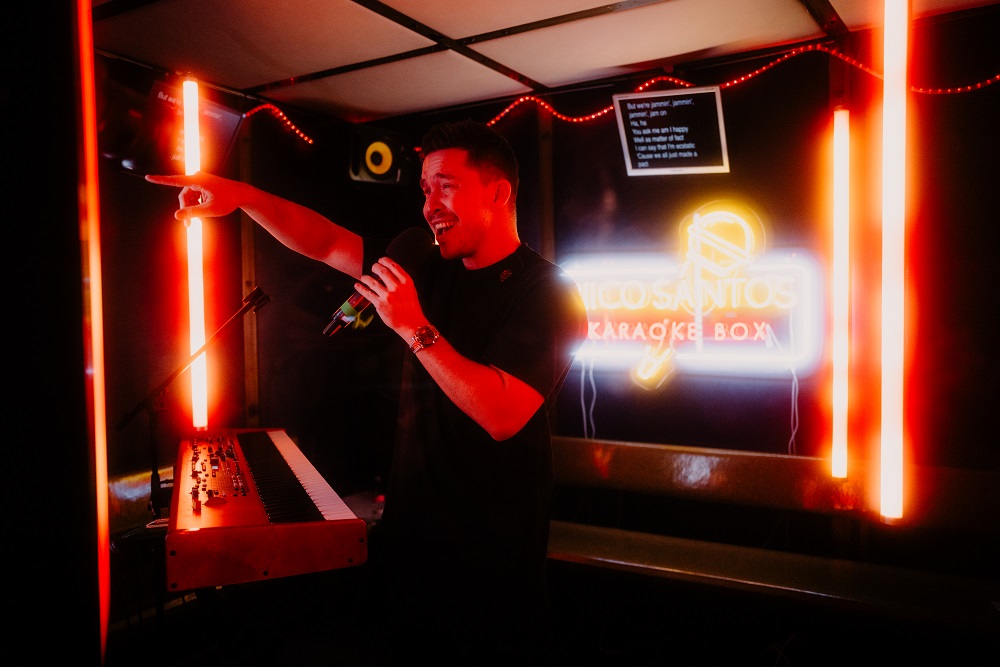 Niko Santos singt in einer Karaokebox mit Neonbeleuchtung