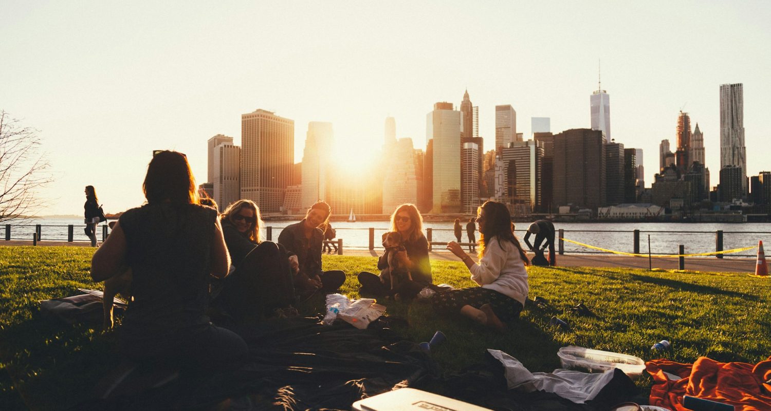Gruppe von Menschen, die auf einer Wiese im Sonnenuntergang sitzt