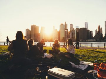 Gruppe von Menschen, die auf einer Wiese im Sonnenuntergang sitzt