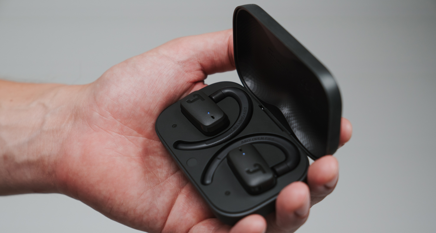 Hand hält schwarzes Ladecase mit Ope-Ear-Kopfhörern AIRY OPEN TWS