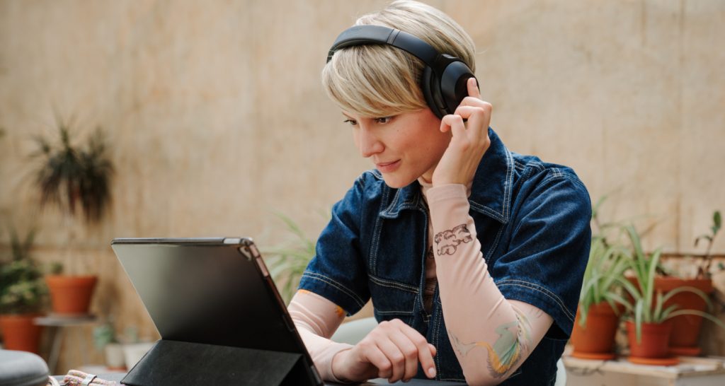 Frau schaut auf ein Tablet und trägt ANC-Kopfhörer REAL BLUE NC 3 von Teufel.