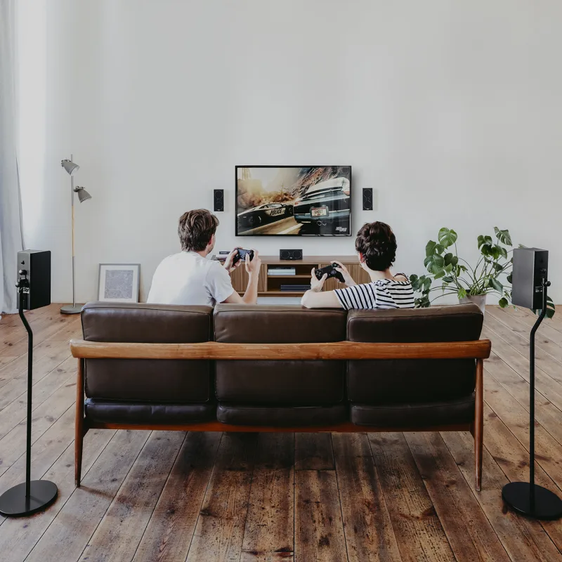 Zwei Personen spielen Videospiele auf einem Sofa in einem modernen Raum.