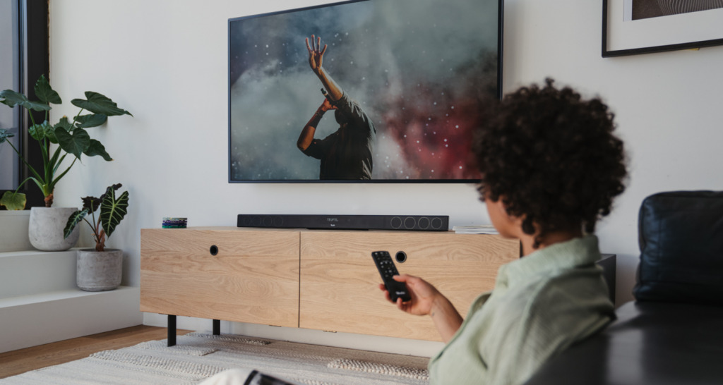 CINEBAR 11 für Dolby Atmos "2.1-Set" Person bedient Fernseher, auf dem Sideboard eine Cinebar 11