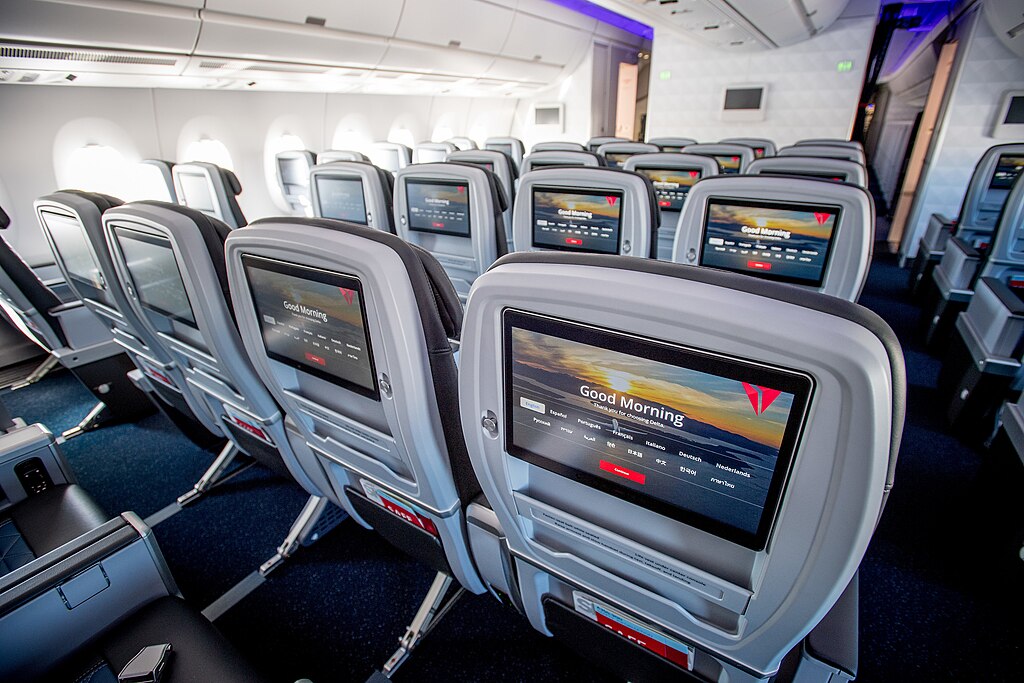 Sitzreihen in einem Flugzeug, Multimedia-Bildschirme an den Vordersitzen.