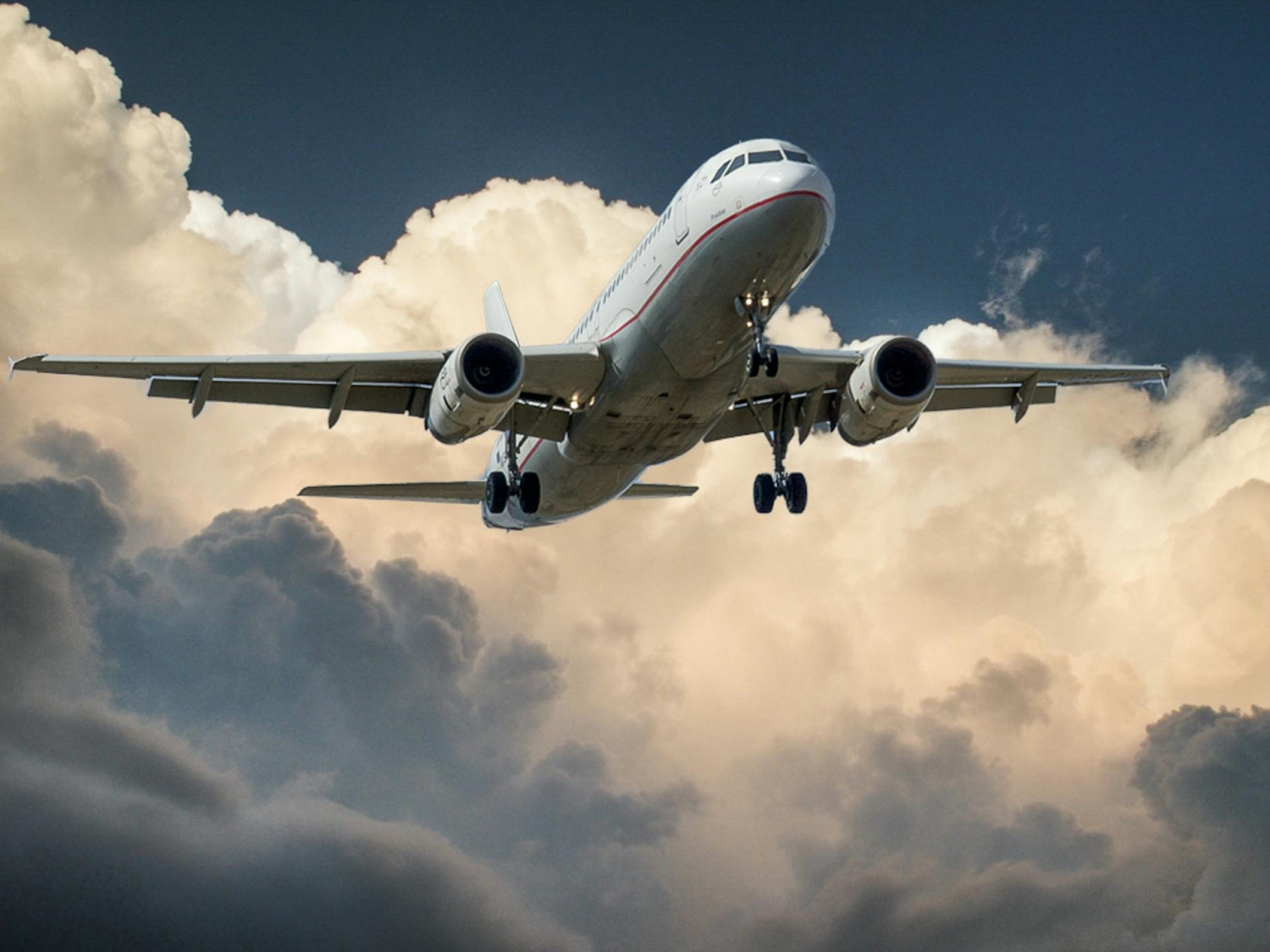Passagierflugzeug im Landeanflug vor einer Wolkenkulisse.