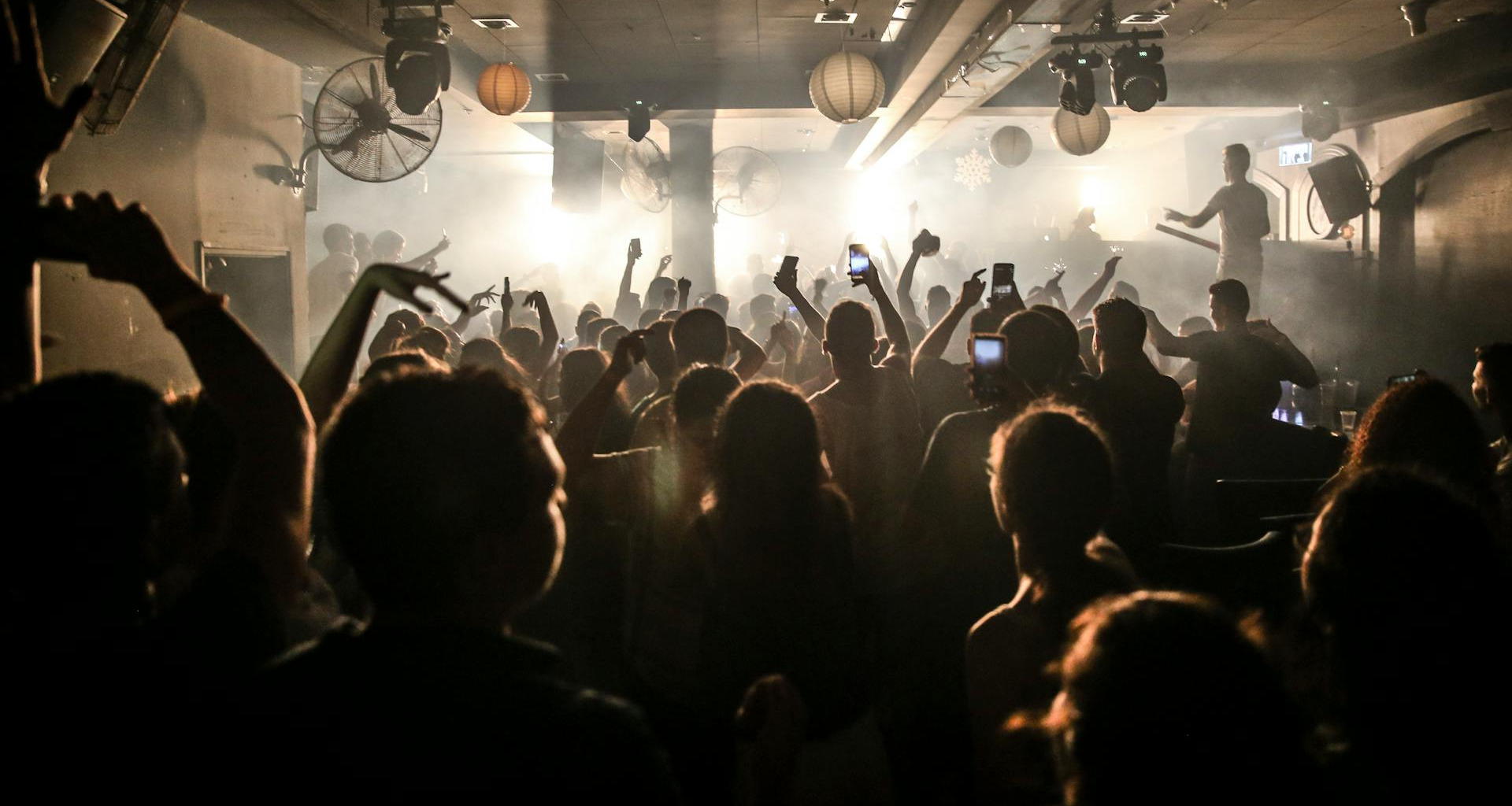 Menschen tanzen in einem Club zu Drum and Bass, umgeben von Licht, Nebel und energiegeladener Stimmung.
