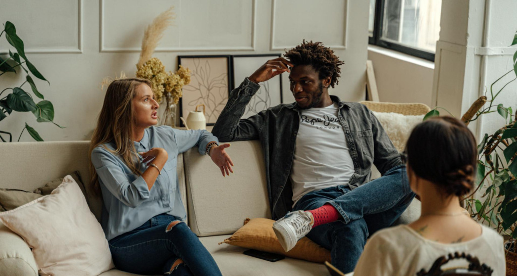 Zwei Personen sitzen auf einem Sofa und diskutieren.